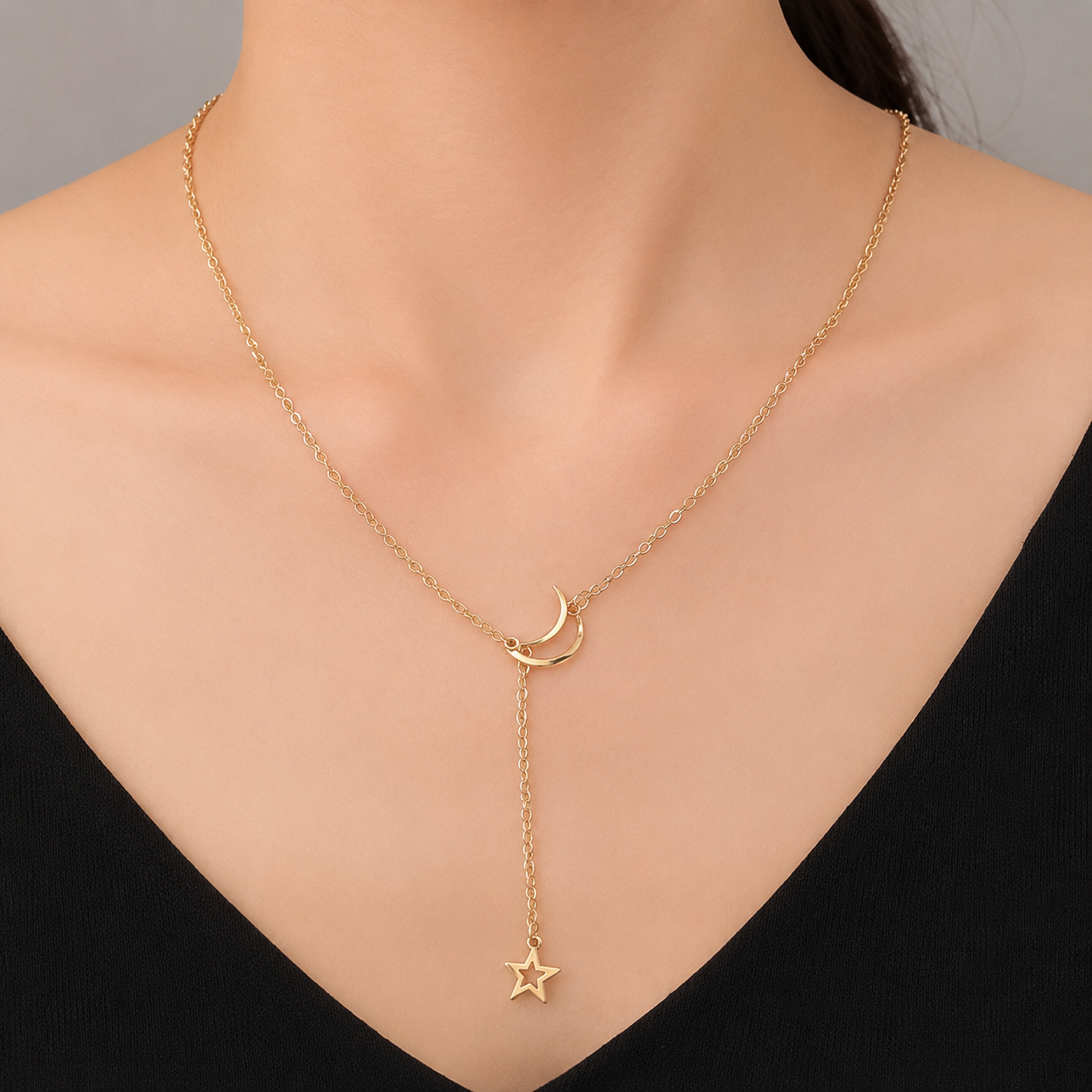 Woman wearing the gold moon and star Y-drop lariat necklace with a black top