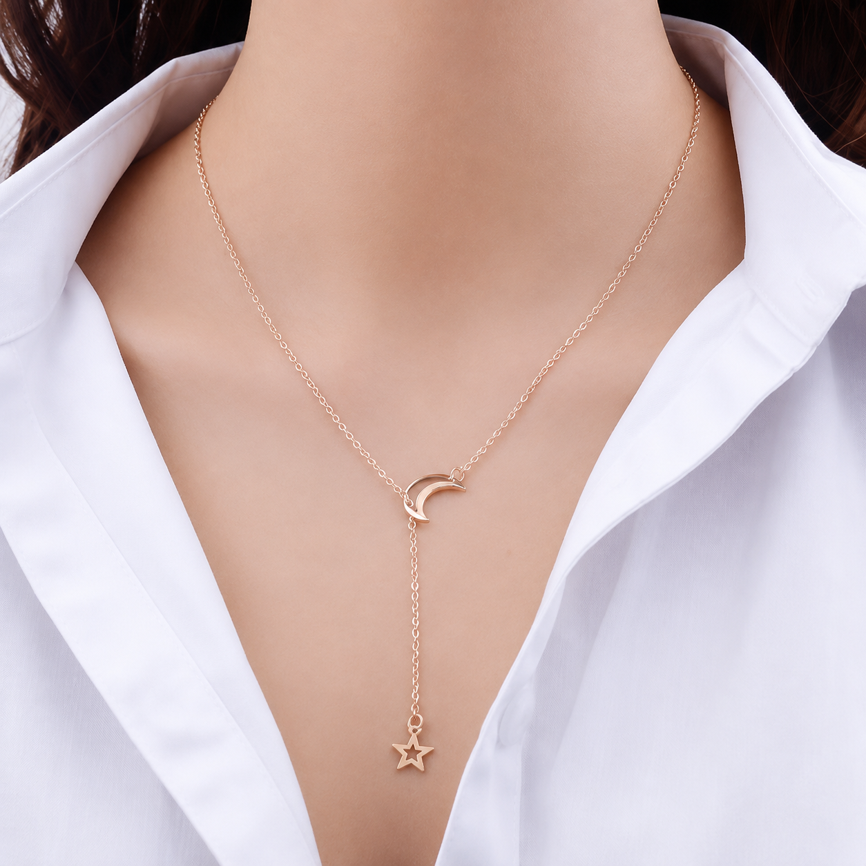 Moon and star lariat necklace worn with an open white shirt collar